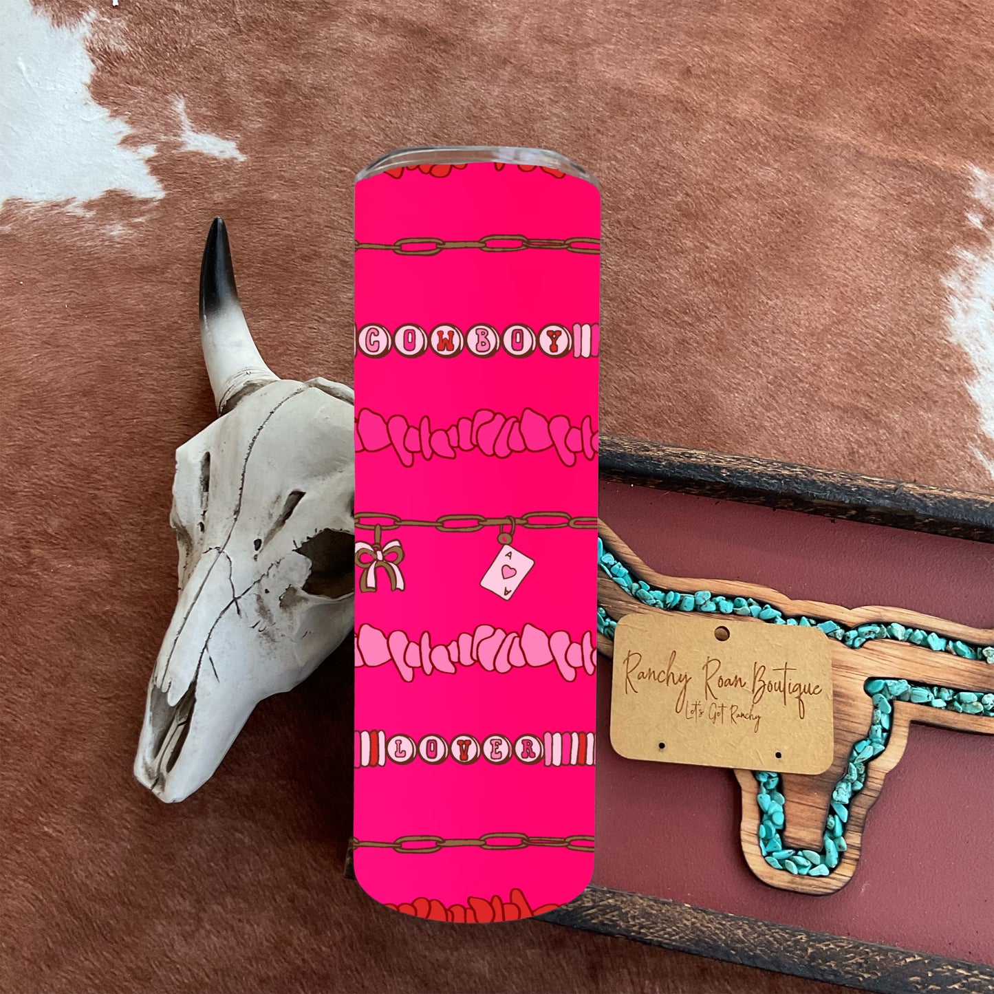 Stainless steel tumbler featuring a bright pink “Cowboy Lover” Western design with chain and charm details.