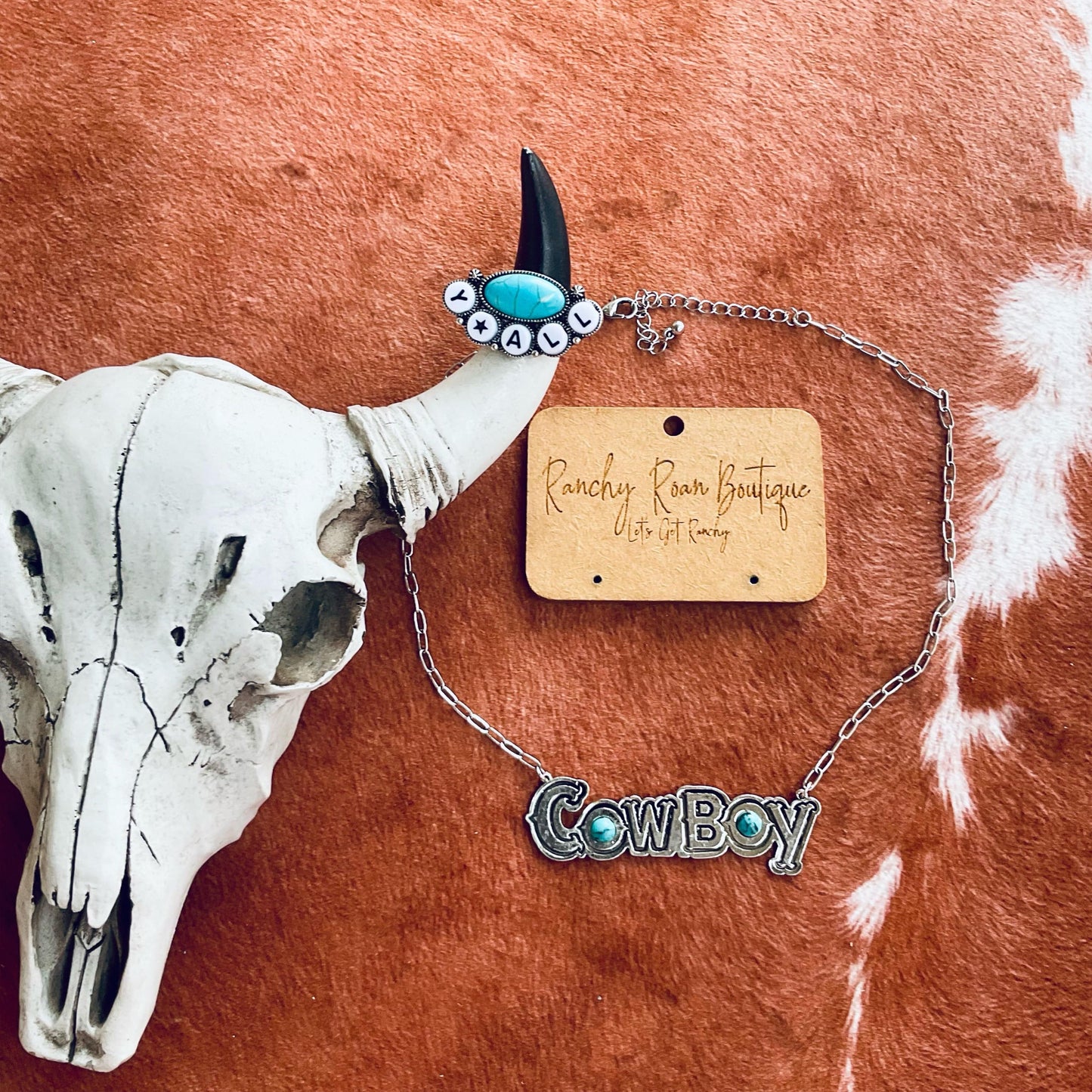 Cowboy necklace with turquoise and burnished silver accents on a 16-inch chain with a 3-inch extender, displayed on a rustic background with a cow skull.