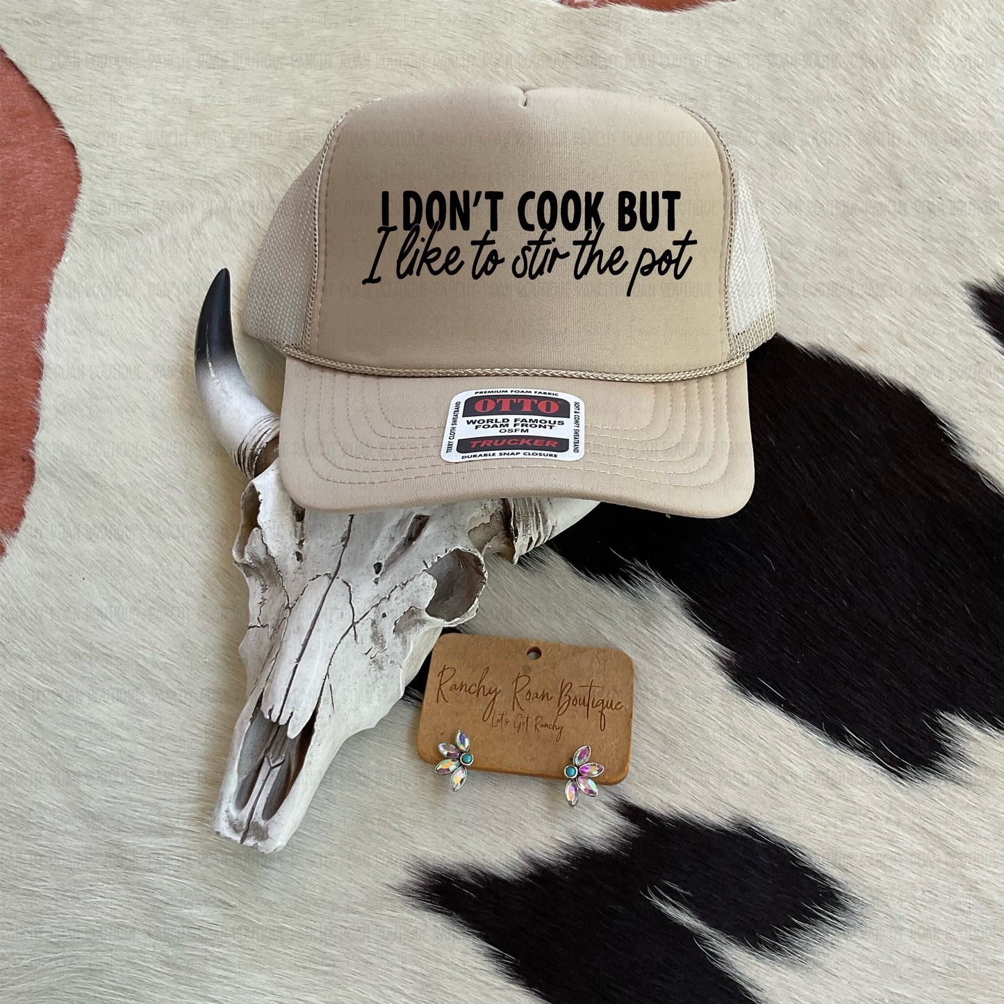 I Don’t Cook, But I Like to Stir the Pot Trucker Hat with Western-style script on a neutral-toned foam-front cap.
