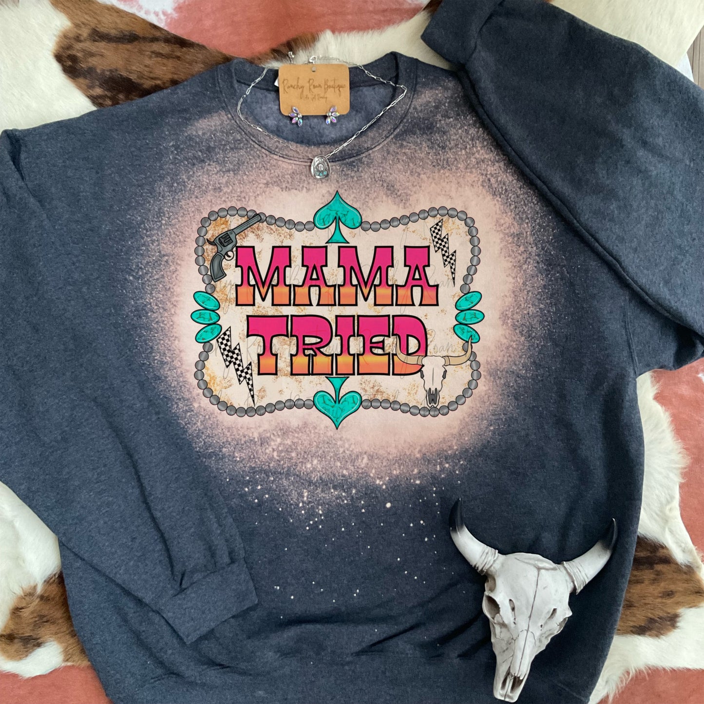 Western-style bleached sweatshirt with “Mama Tried” graphic, styled with cow skull decor and turquoise jewelry.