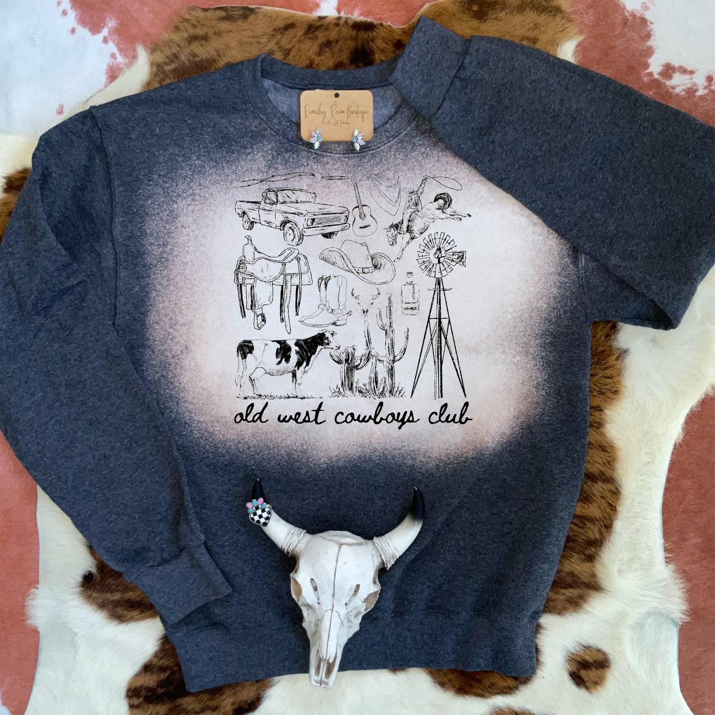 Black Heather sweatshirt with bleach detailing, featuring a nostalgic ranch-life sketch and “Old West Cowboys Club” text.