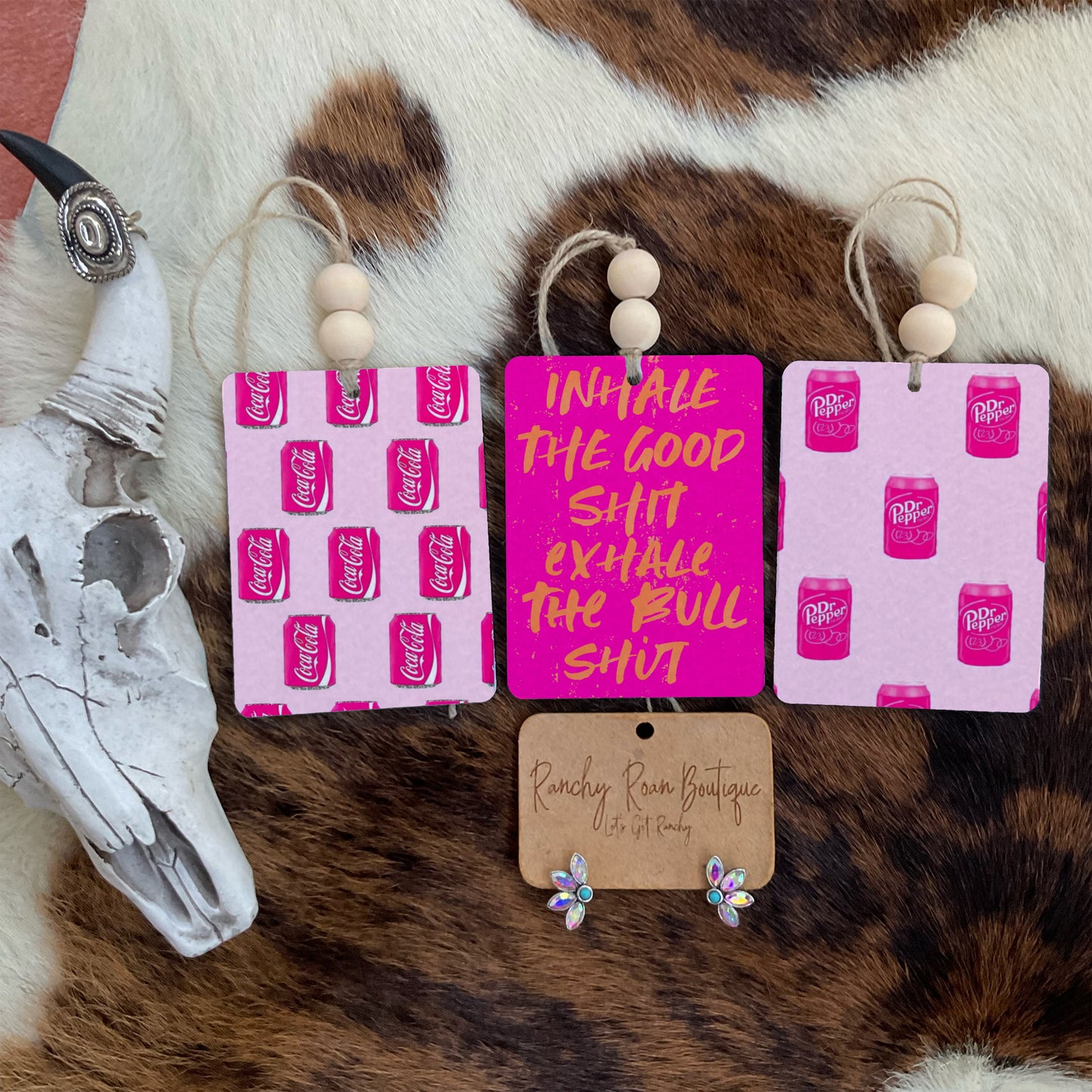 Set of three soda-themed air fresheners featuring Coca-Cola pop art, โInhale the Good Sh*tโ mantra, and Dr Pepper design with rustic wooden bead accents.