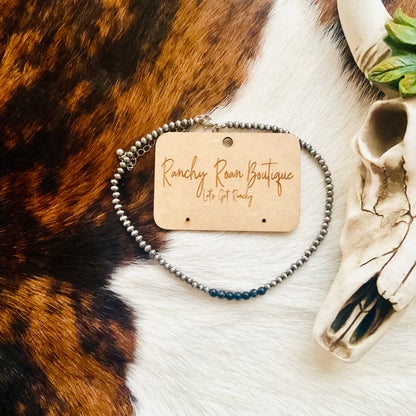 4mm Navajo Style Pearl Choker Necklace in burnished silver with black, displayed with a decorative skull on a cowhide background.