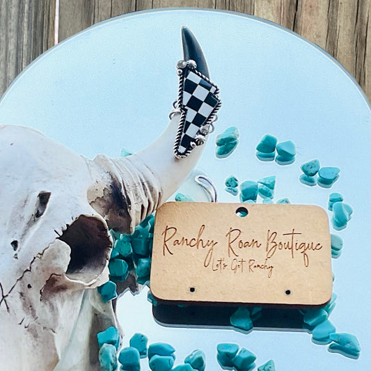 Black-and-white checker pattern thunder cuff ring displayed on a decorative horn with turquoise stones, showcasing its bold Western style and intricate design.