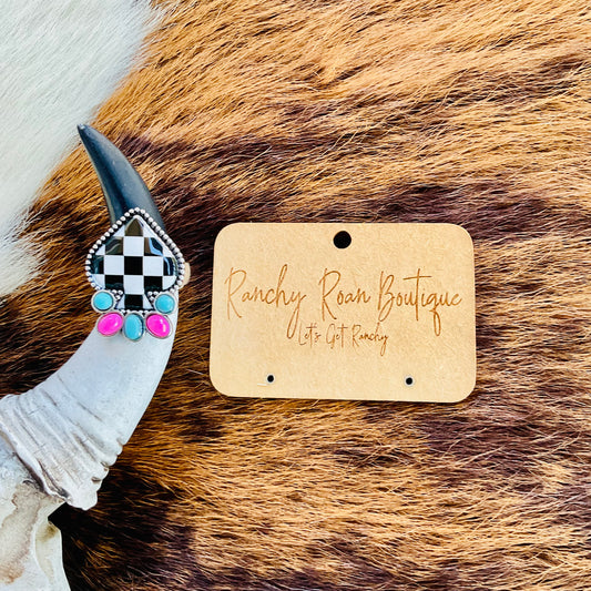 Western Checker Spade Stretch Ring displayed on a cowhide background, highlighting its bold black-and-white design.