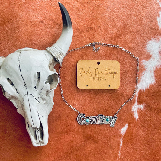 Cowboy necklace with turquoise and burnished silver accents on a 16-inch chain with a 3-inch extender, displayed on a rustic background with a cow skull.