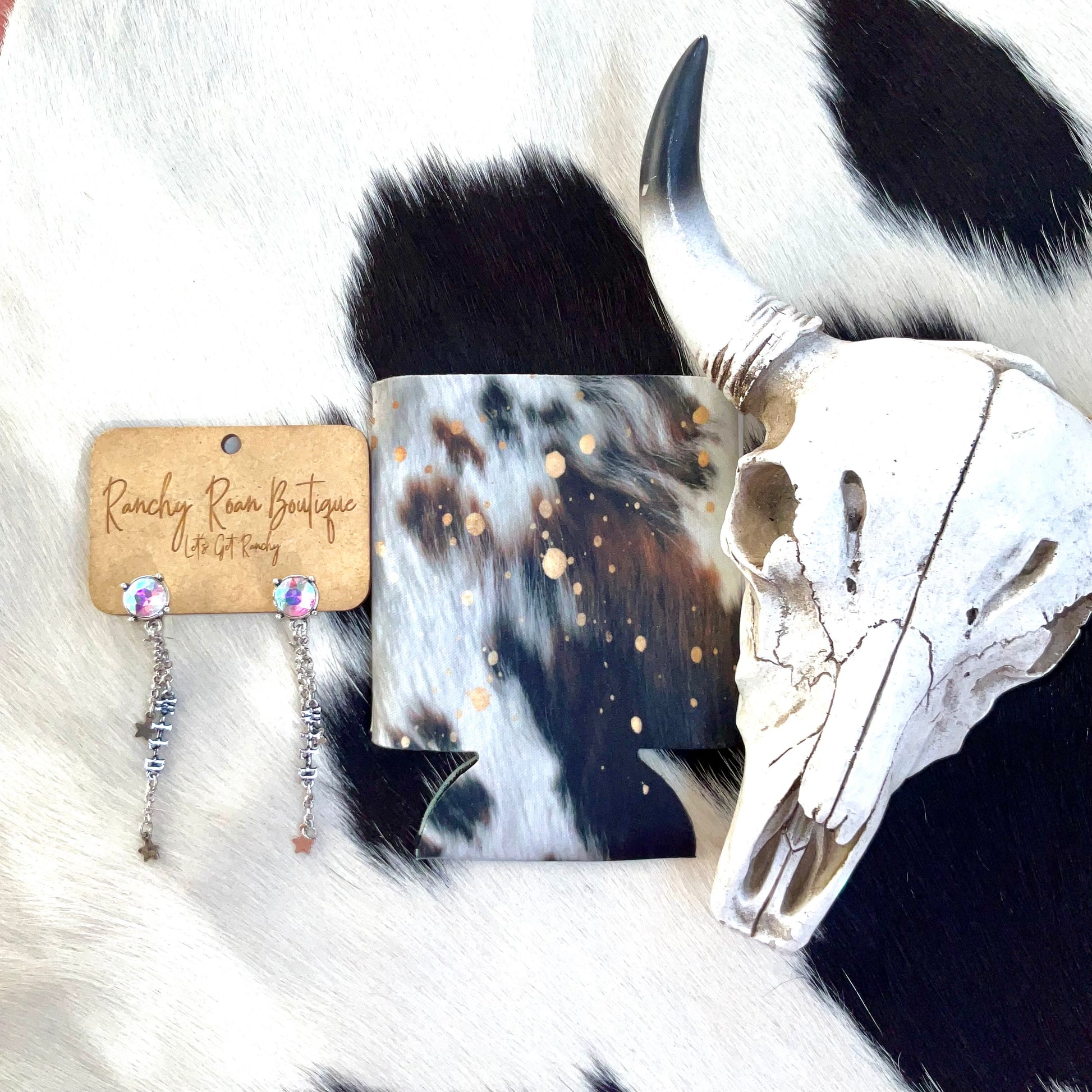 Rustic cowhide-patterned koozie with gold accents, styled with a Western skull decor for a rugged, authentic look.