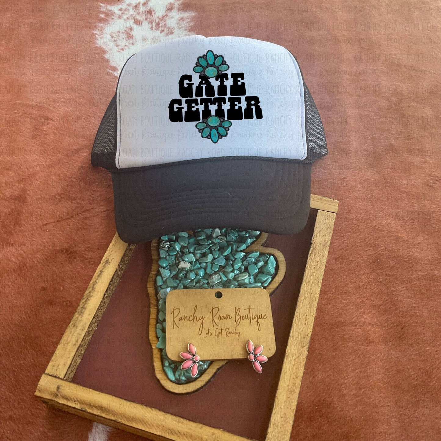 Gate Getter Foam Front Trucker Hat with bold turquoise concho graphic and Western text, styled on a rustic background with Western accessories.