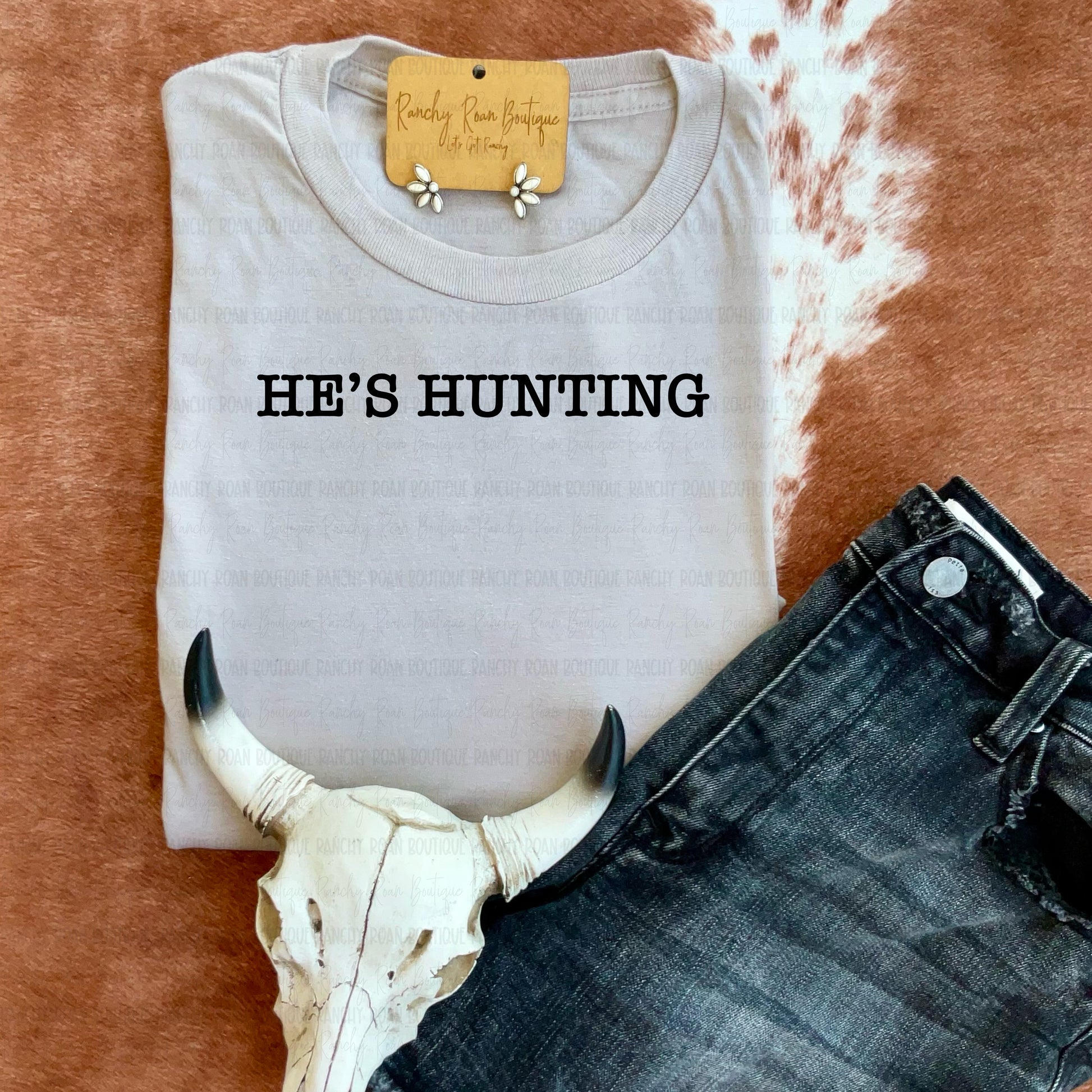 Sand sweatshirt with “He’s Hunting” text styled with denim and cow skull accent.
