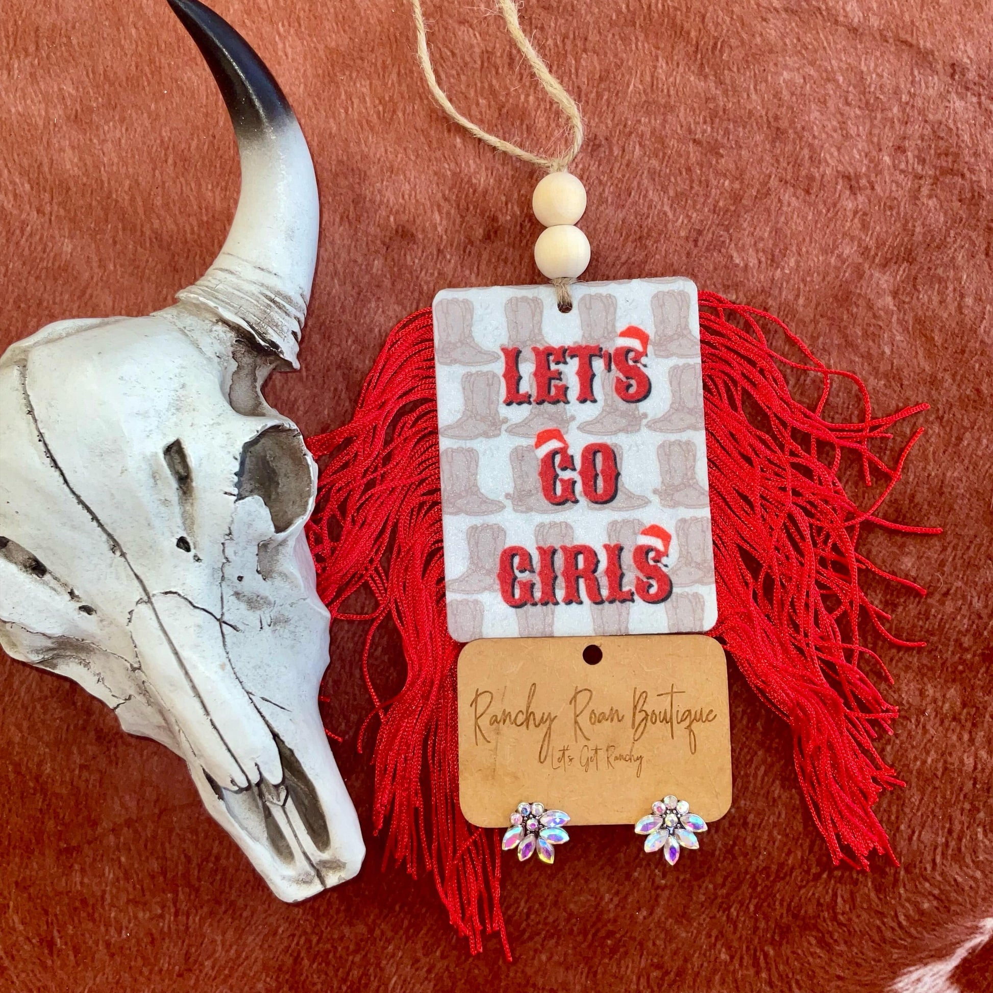 Holiday Western Double-Sided Felt Freshies featuring designs like “Let’s Go Girls” and “Santa,” displayed with colorful fringe and bead accents on a rustic background with a cow skull.