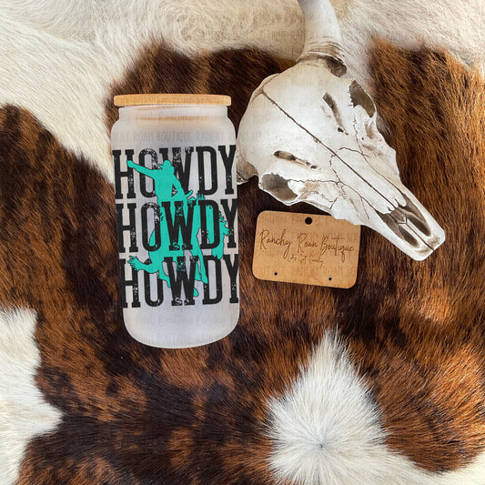 Howdy Bucking Bronc Glass Tumbler with bamboo lid, displayed next to Western skull decor on a cowhide rug.