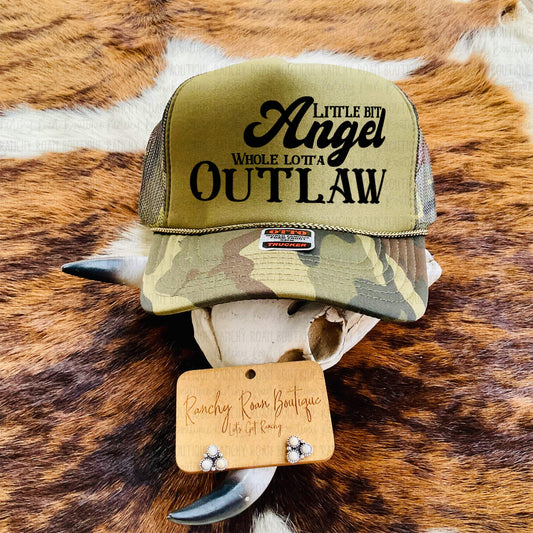 Little Bit Angel, Whole Lotta Outlaw Trucker Hat featuring bold black text on an olive background, styled with rustic Western accessories.