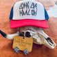 Close-up view of the “Long Live Feral Kids” trucker hat resting on a cow skull, featuring bold text and vibrant red brim with a breathable mesh back.
