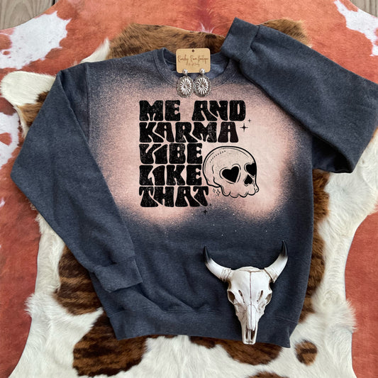 Dark bleached sweatshirt featuring a retro skull graphic with “Me and Karma Vibe Like That” text, laid flat on cowhide for a Western look.