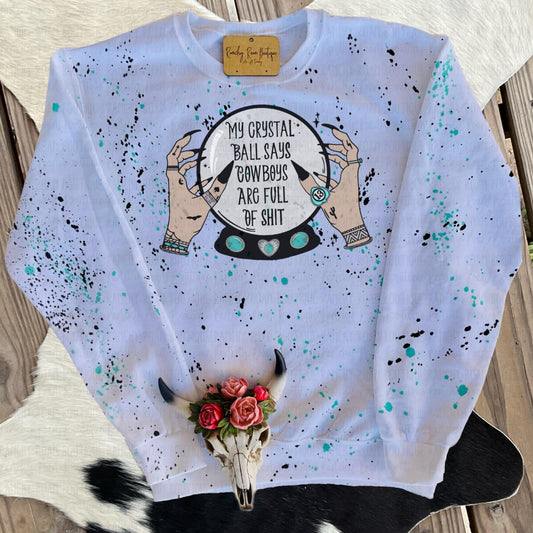White sweatshirt with turquoise and black paint splatter, featuring “My Crystal Ball Says Cowboys Are Full of Shit” Western Halloween-themed sublimation graphic, displayed flat.