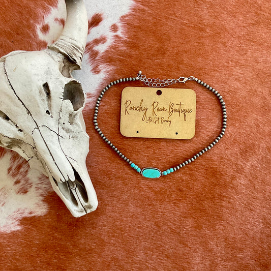  Burnished silver-tone beaded choker featuring a turquoise-colored stone centerpiece, displayed with a Western cow skull background.