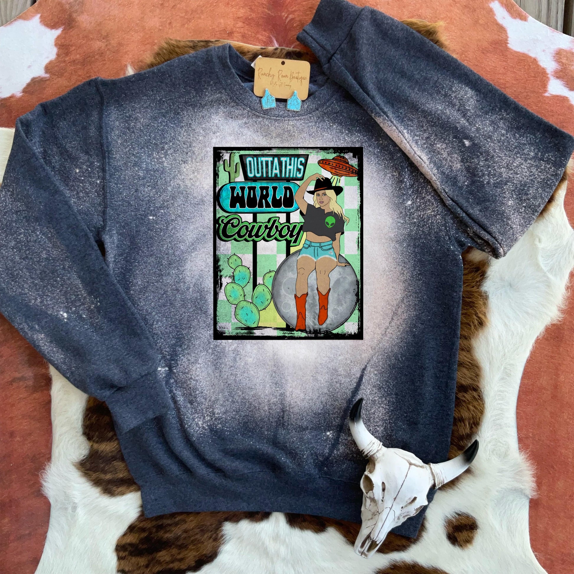 Outta_This_World_Cowboy_Western_Sweatshirt: Front view of the Outta This World Cowboy Bleached Sweatshirt featuring a vibrant sublimation print of a cowgirl on a moon with cacti and neon accents.