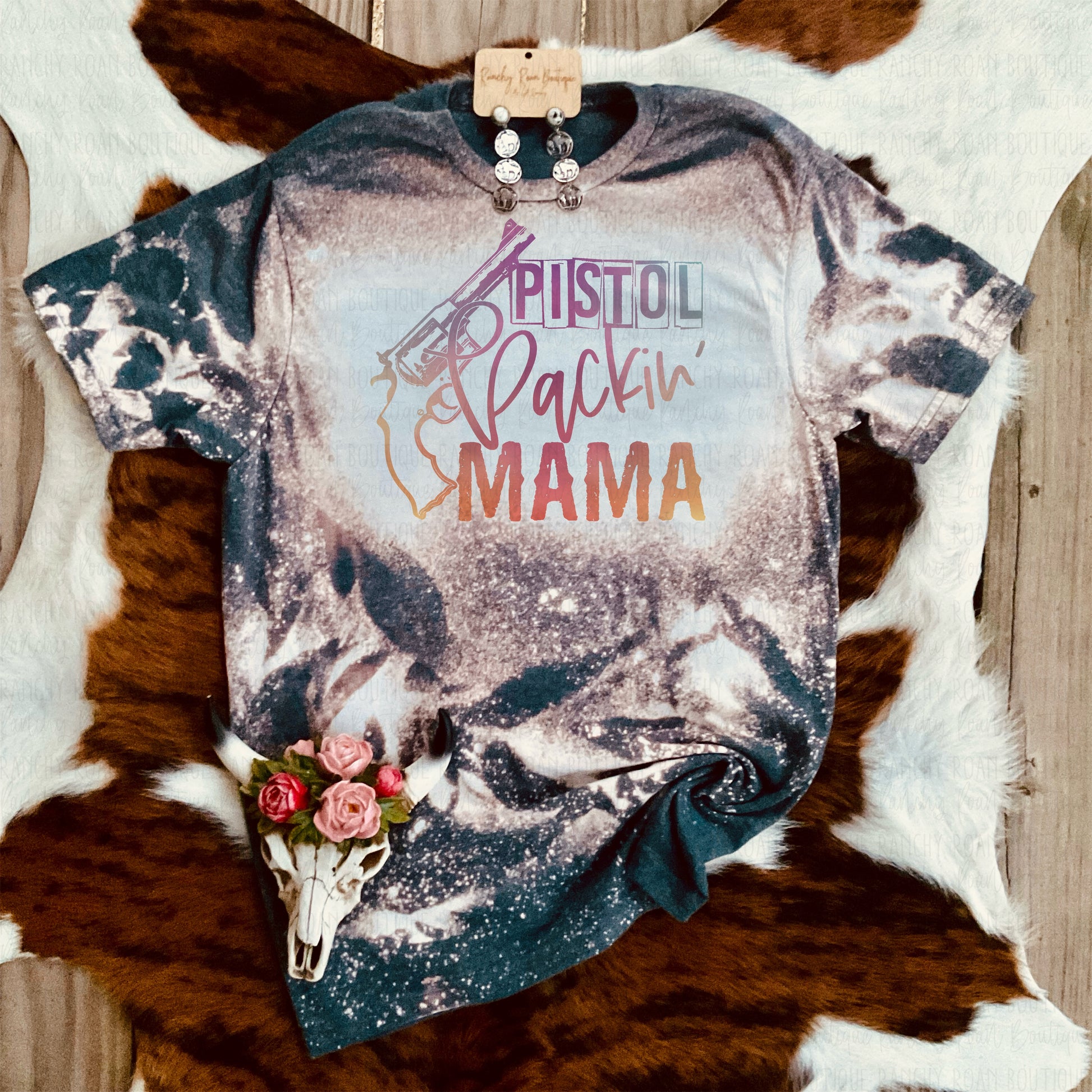 Unisex crew t-shirt featuring the text “Pistol Packin’ Mama” with a vibrant pistol graphic, displayed with a unique bleach splatter pattern.