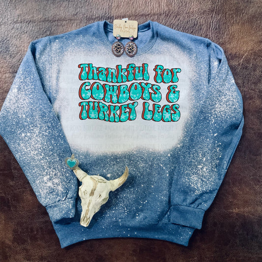 Bleached blue sweatshirt with the phrase “Thankful for Cowboys &amp; Turkey Legs” in turquoise lettering, displayed with Western earrings and a decorative skull.