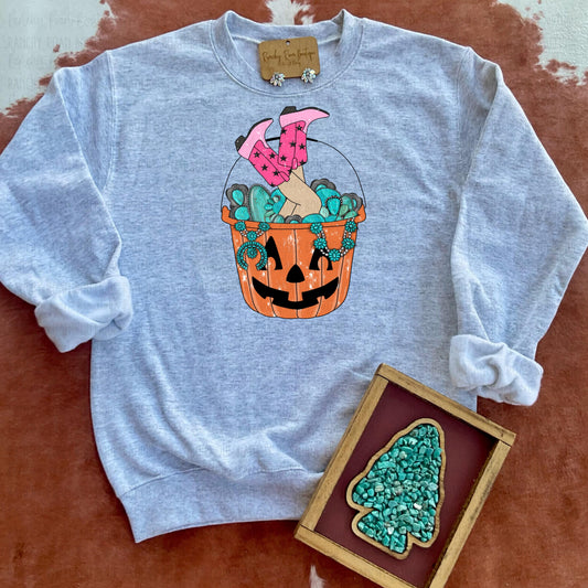 A light heather gray sweatshirt from Ranchy Roan Boutique featuring a Halloween-themed bucket filled with turquoise accents and pink cowgirl boots, giving it a playful Western twist.