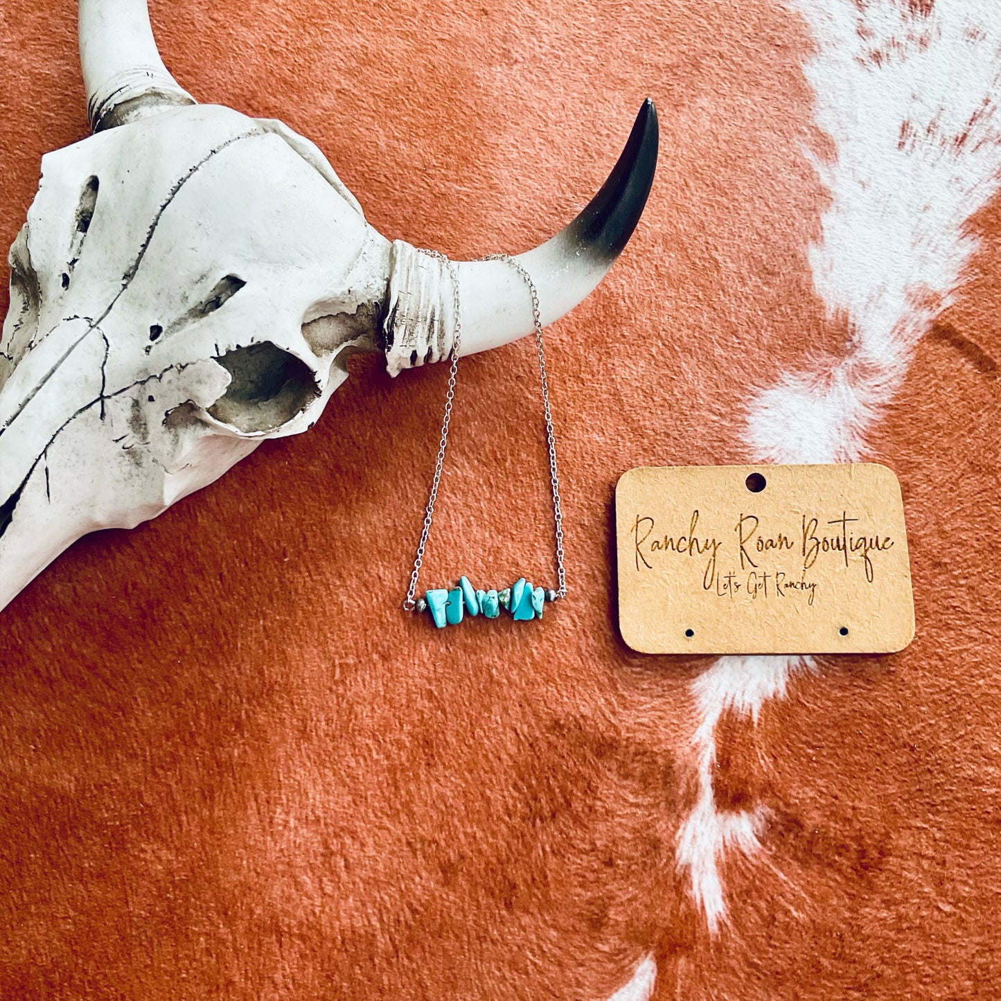 Turquoise Chip Stone Bar Necklace on a 16-inch chain with a 3-inch extender, displayed on a rustic background with a cow skull, ideal for western boutiques