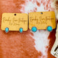 Pair of turquoise stud earrings displayed on Ranchy Roan Boutique branding card.