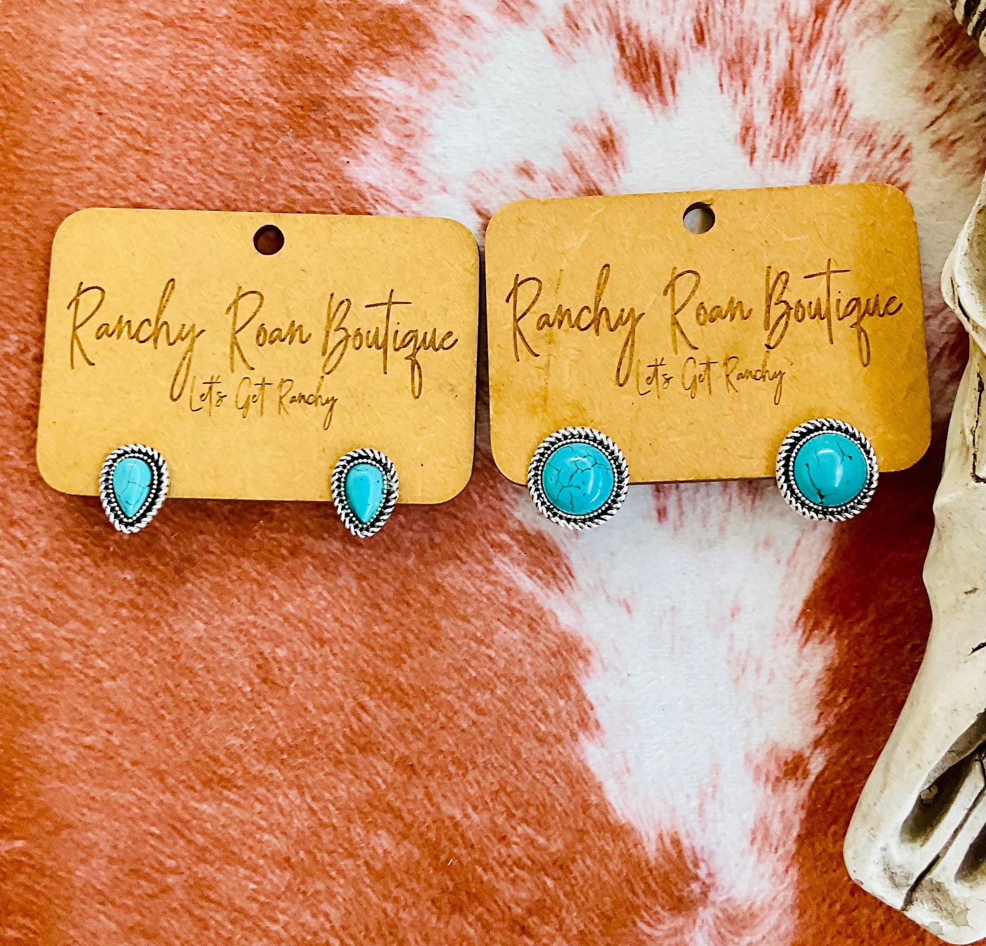 Pair of turquoise stud earrings displayed on Ranchy Roan Boutique branding card.