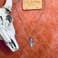 Turquoise cactus pendant necklace displayed on a soft orange cowhide background with a decorative cow skull.