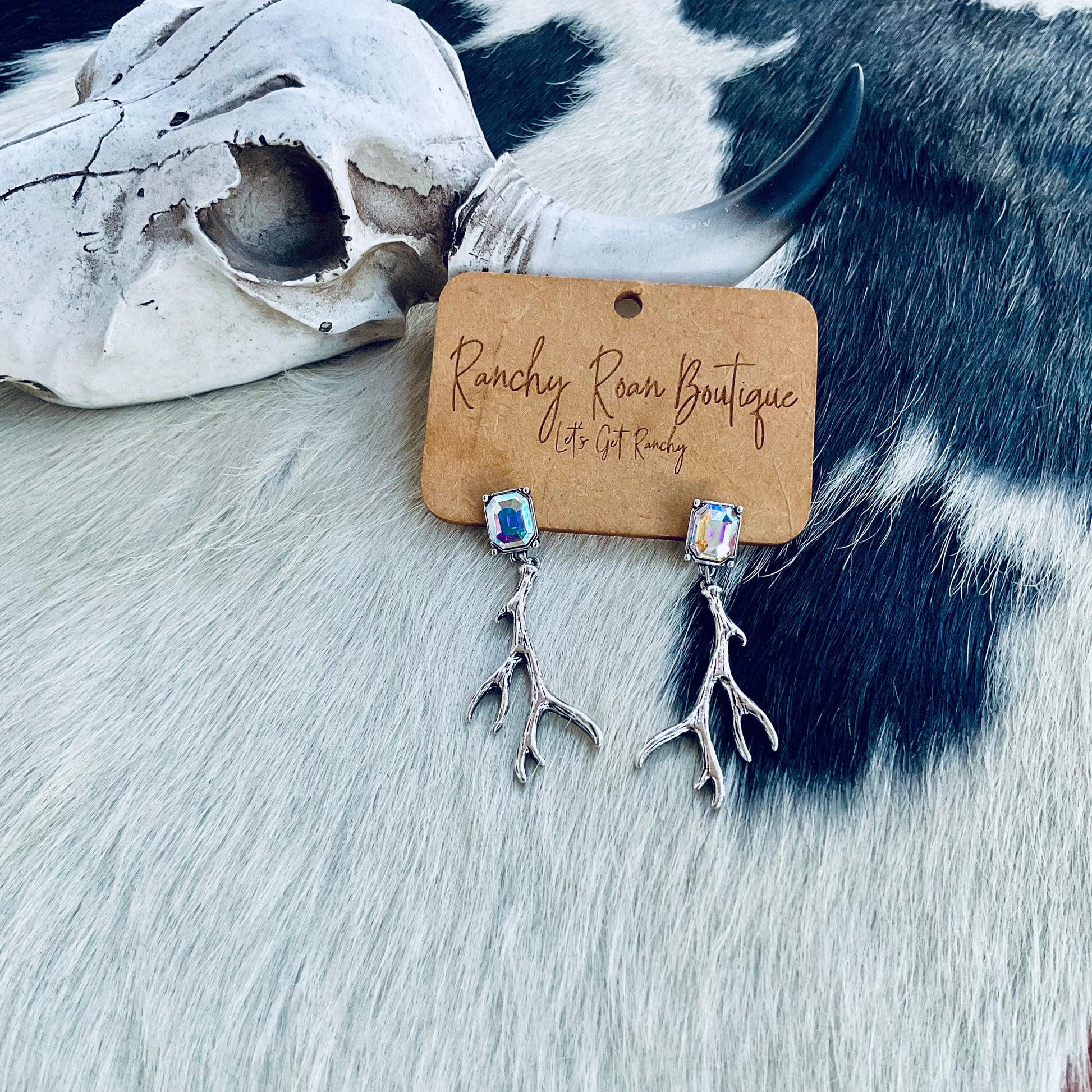 Western Antler Stone Stud Earrings featuring burnished silver antlers with sparkling AB stones, styled against a rustic Western backdrop.