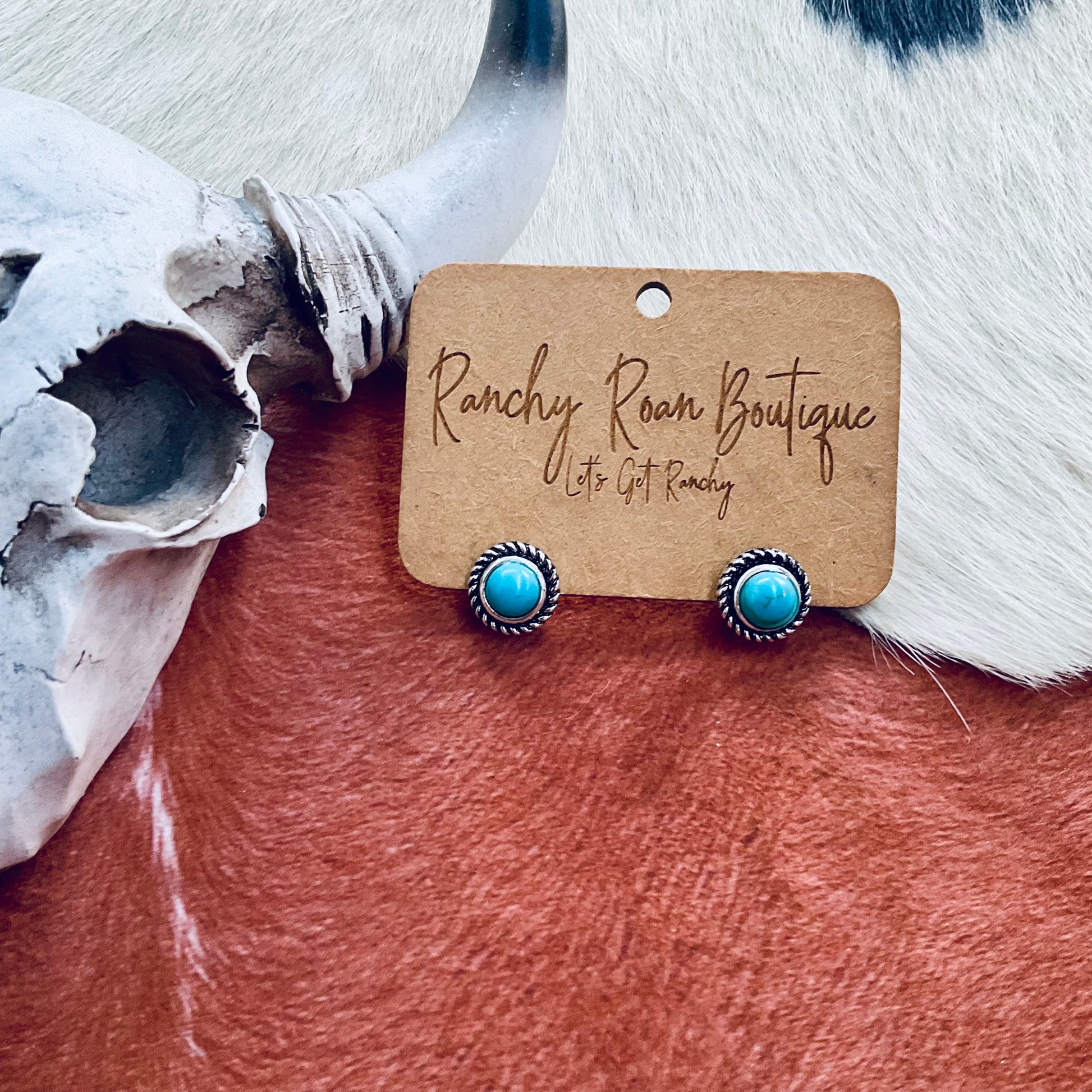 Western Design Turquoise Stone Stud Earrings featuring burnished silver settings and turquoise stones, styled with rustic Western accessories.