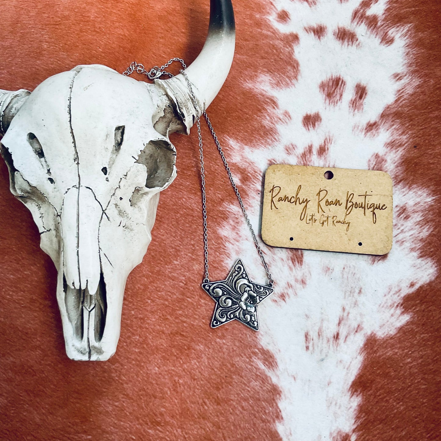 Western star pendant necklace displayed with a 16” chain and 3” extension on a rustic background.