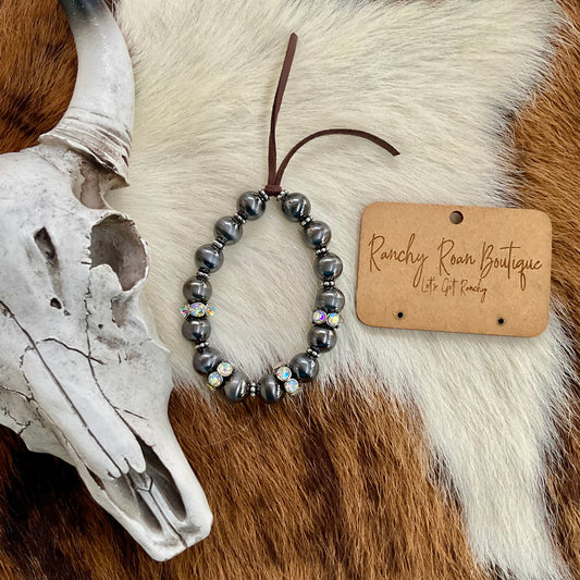  Close-up of the burnished pearl bracelet with sparkling stones, styled on a cowhide backdrop.