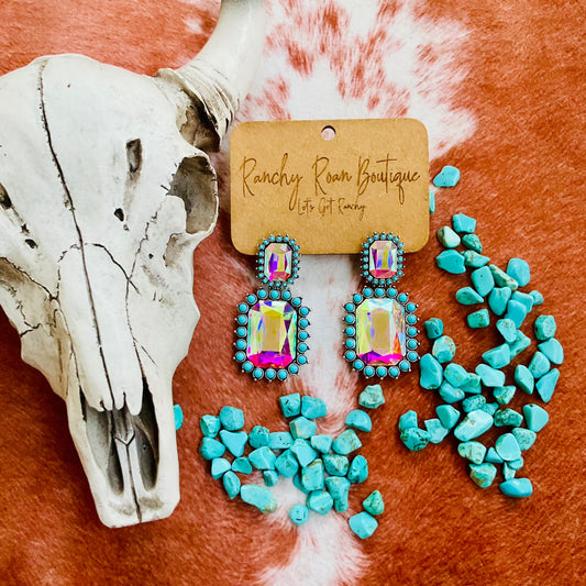 Close-up of Western octagon stone stud earrings with turquoise accents and radiant AB stones, styled with a cow skull and turquoise stones for a bold Western look.