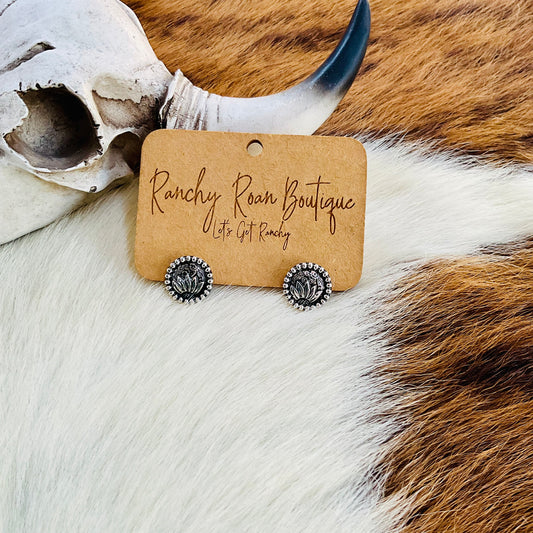 Sunflower earrings next to a decorative skull, showcasing their delicate design.